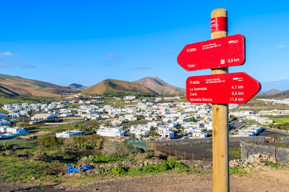 In focus trekking sign with blurred Uga village in background, Lanzarote, Canary Islands, Spain